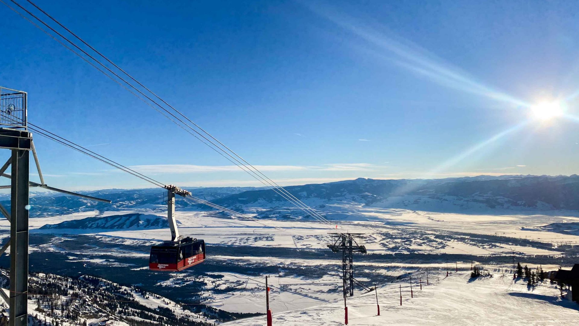 A chairlift on a snowy mountain with the sun low in the sky.