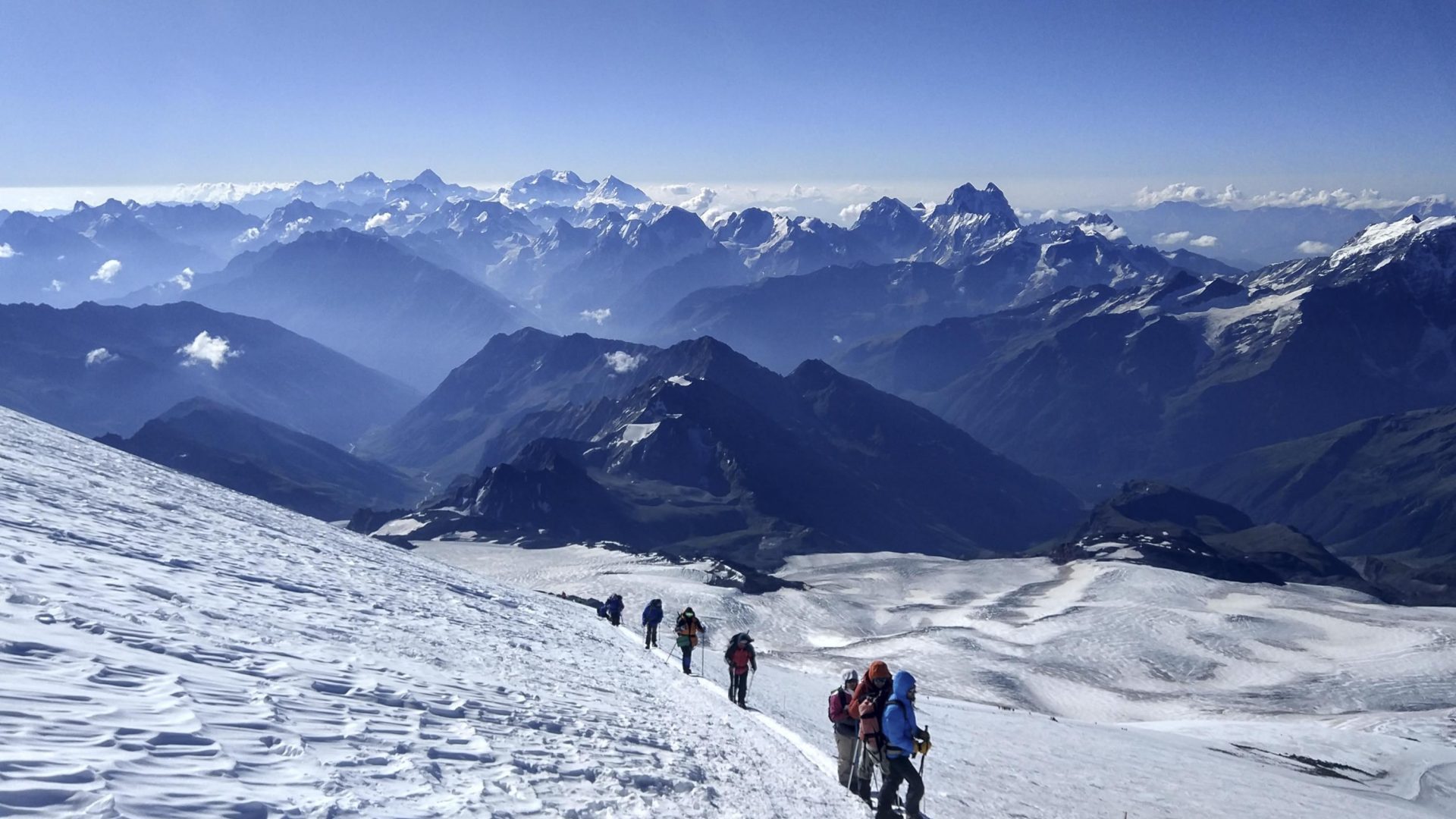 Hikers walk single file through the snow on Mount Elbrus.