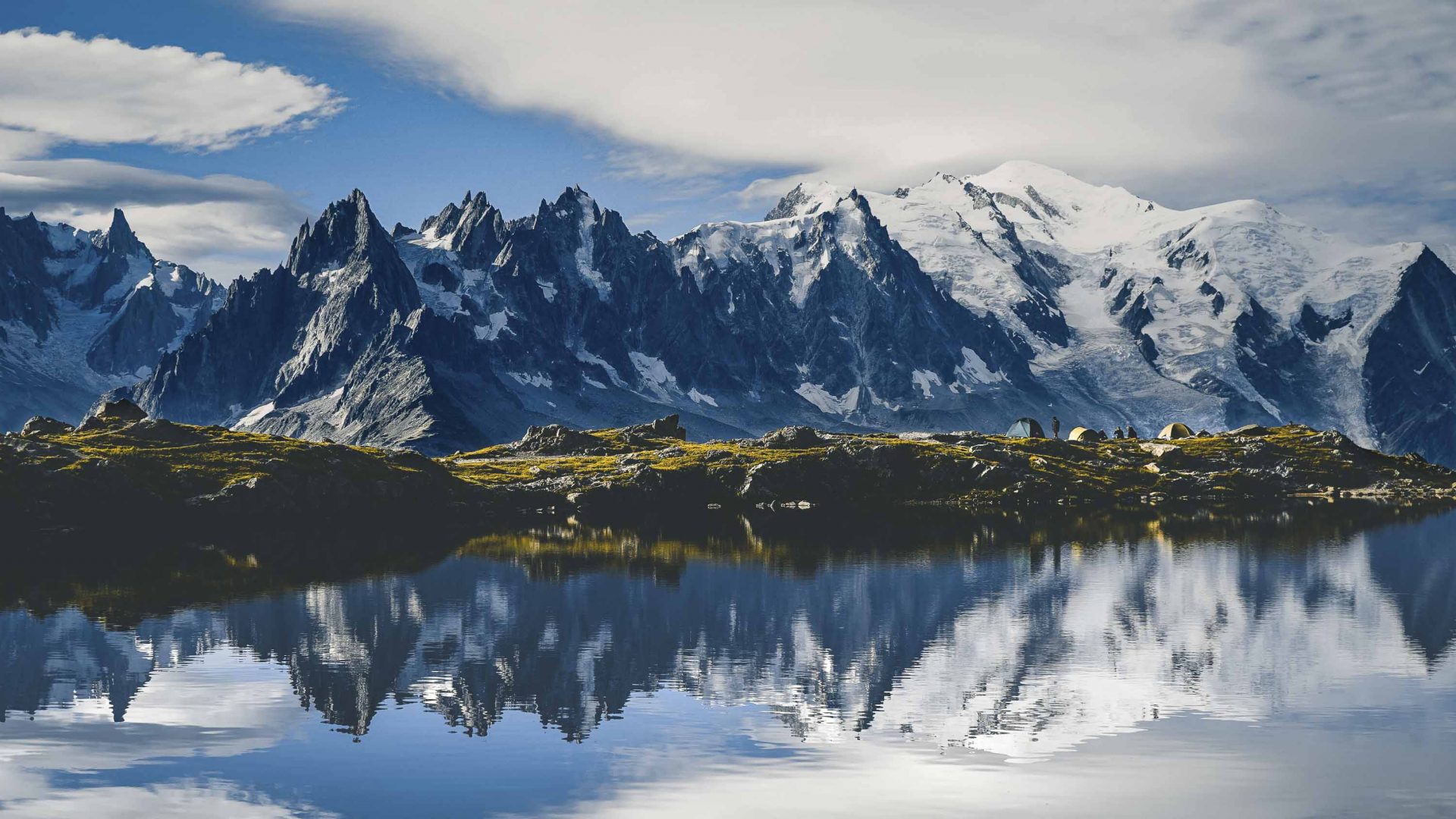 Mont Blanc in the background covered in snow with a lake in the foreground showing the mountain reflections.