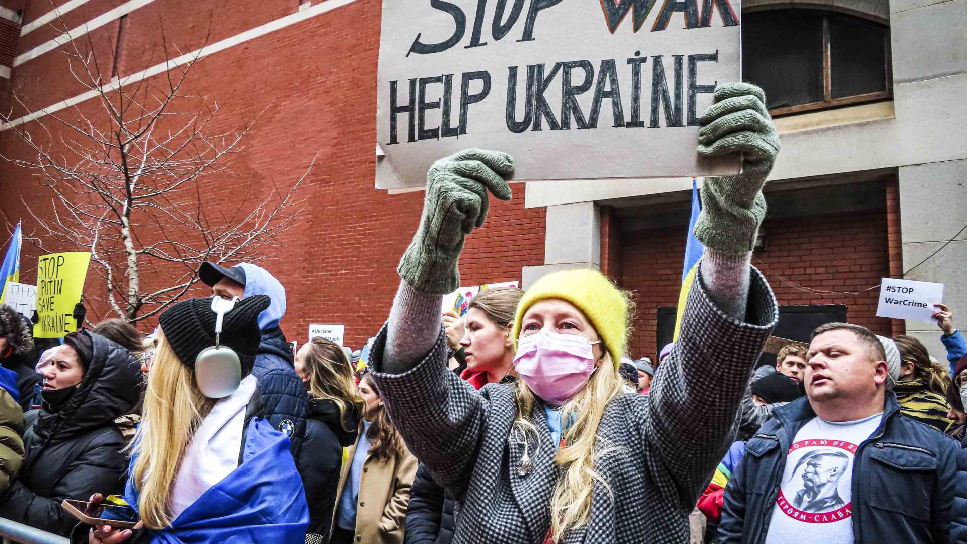 A protestor holds a sign reading 'Stop war, help Ukraine'.