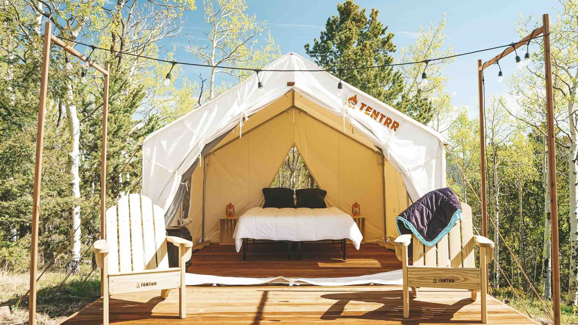The open flaps of a tent reveal a double bed inside.