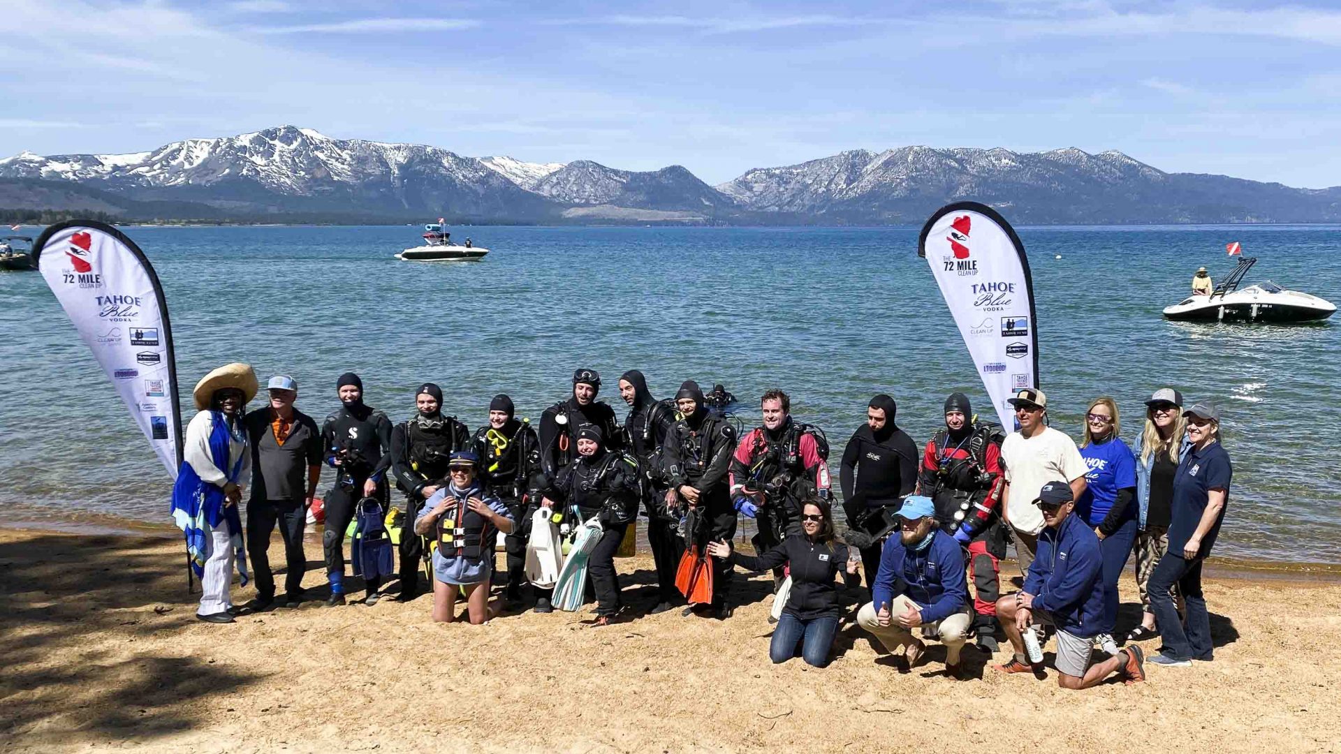 A group of divers smile for the camera on the shore of the lake.