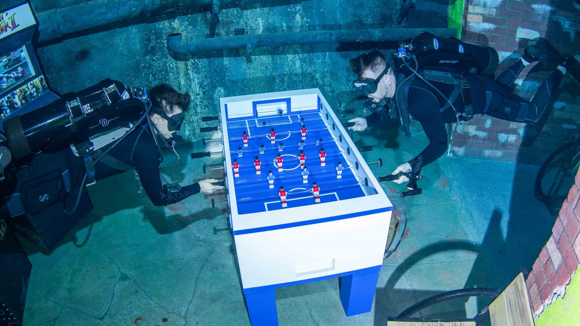 Two divers play an underwater game of foosball or table football.