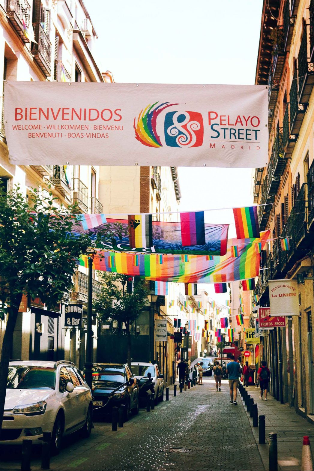 A narrow Spanish street lined with pride flags.