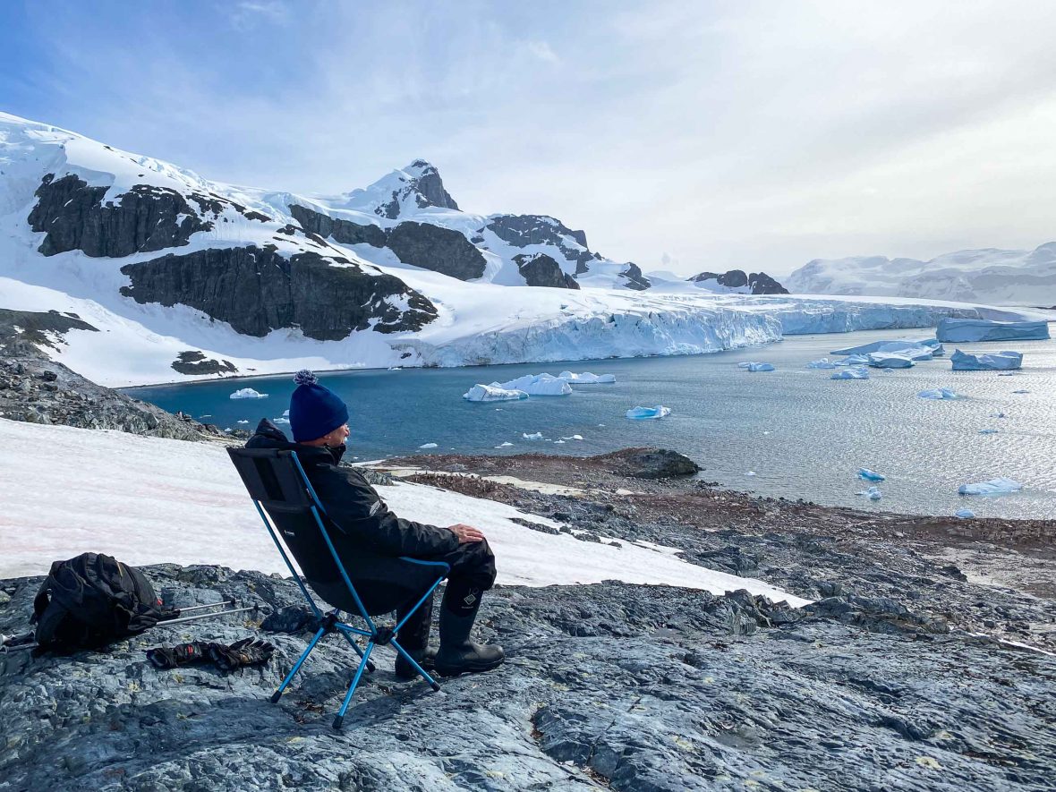 Robby sits on a chair overlooking the glaciers of Antarctica.
