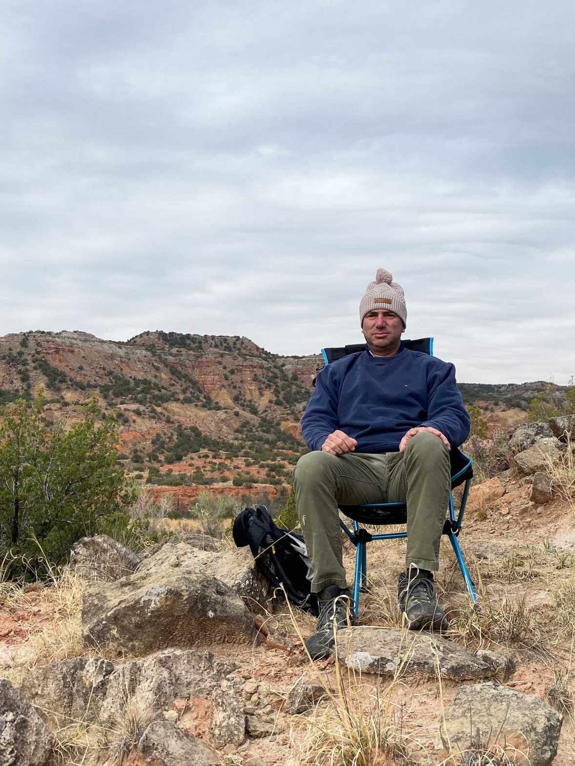 Robby in his chair with fairly dry hills behind him.