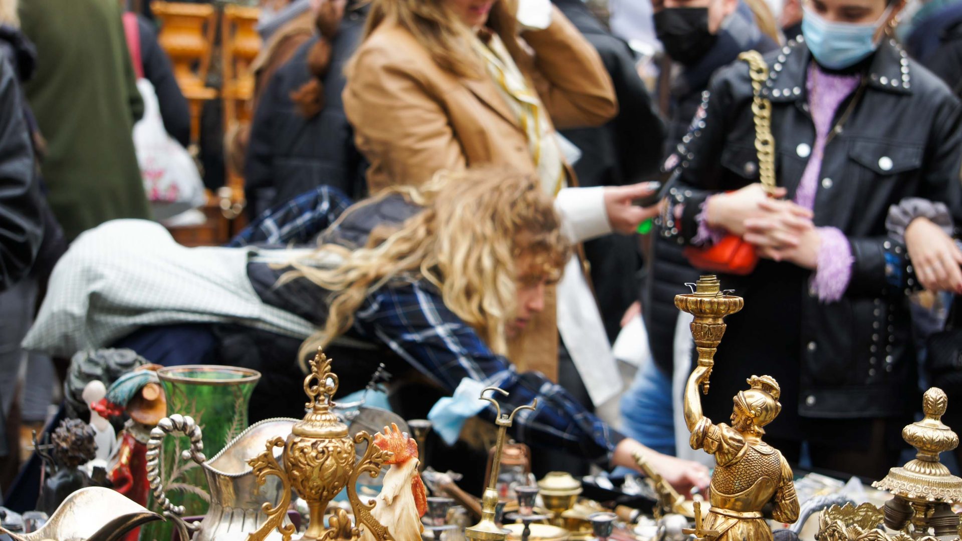 A person looks at objects at a market stall.