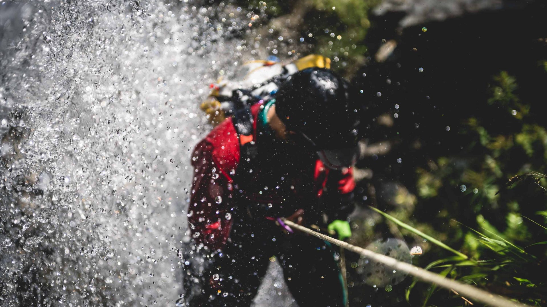 Water sprays up as a person is seen canyoning down what is presumably a waterfall.
