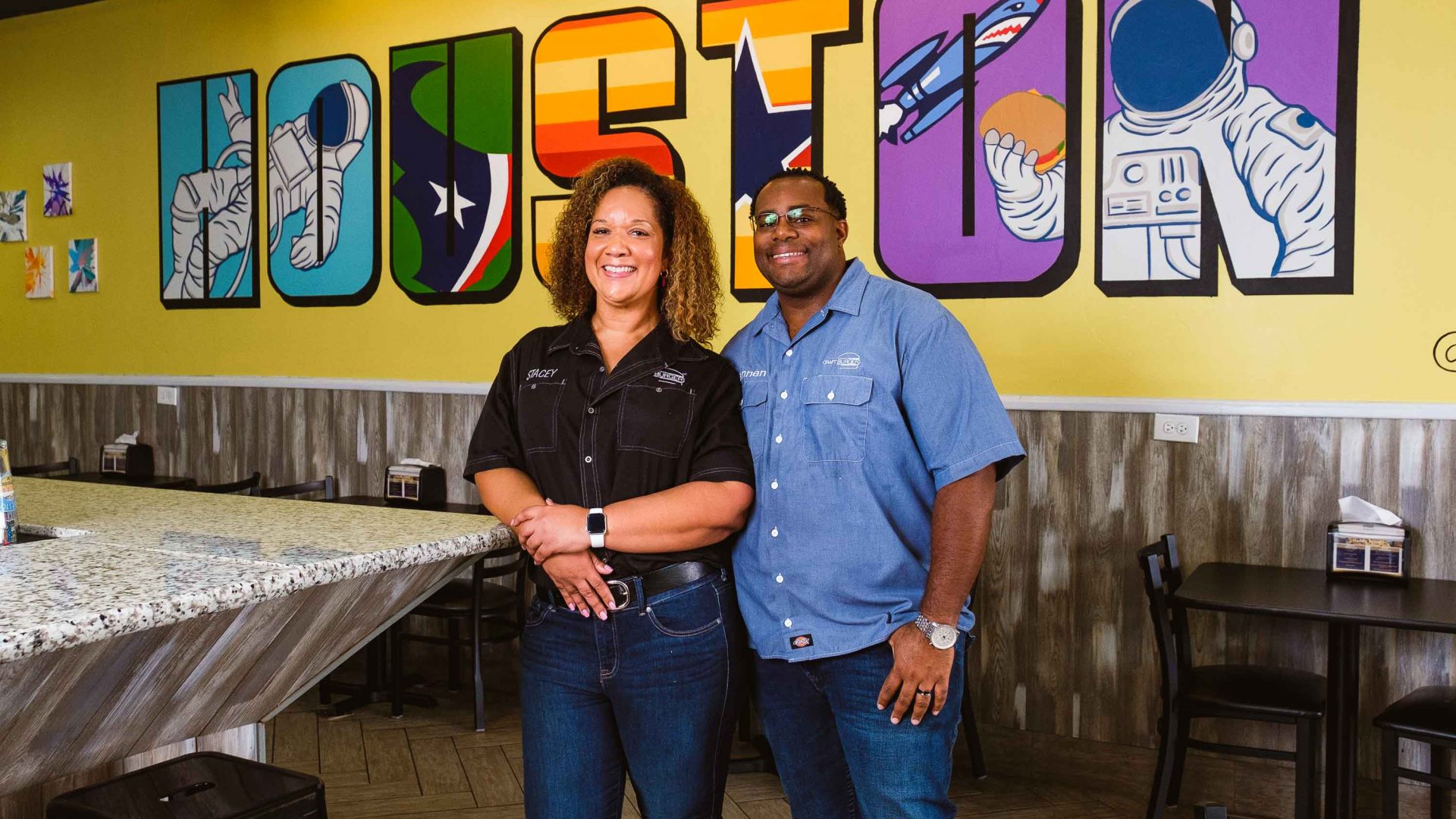 A couple stand in front of a wall that says Houston.