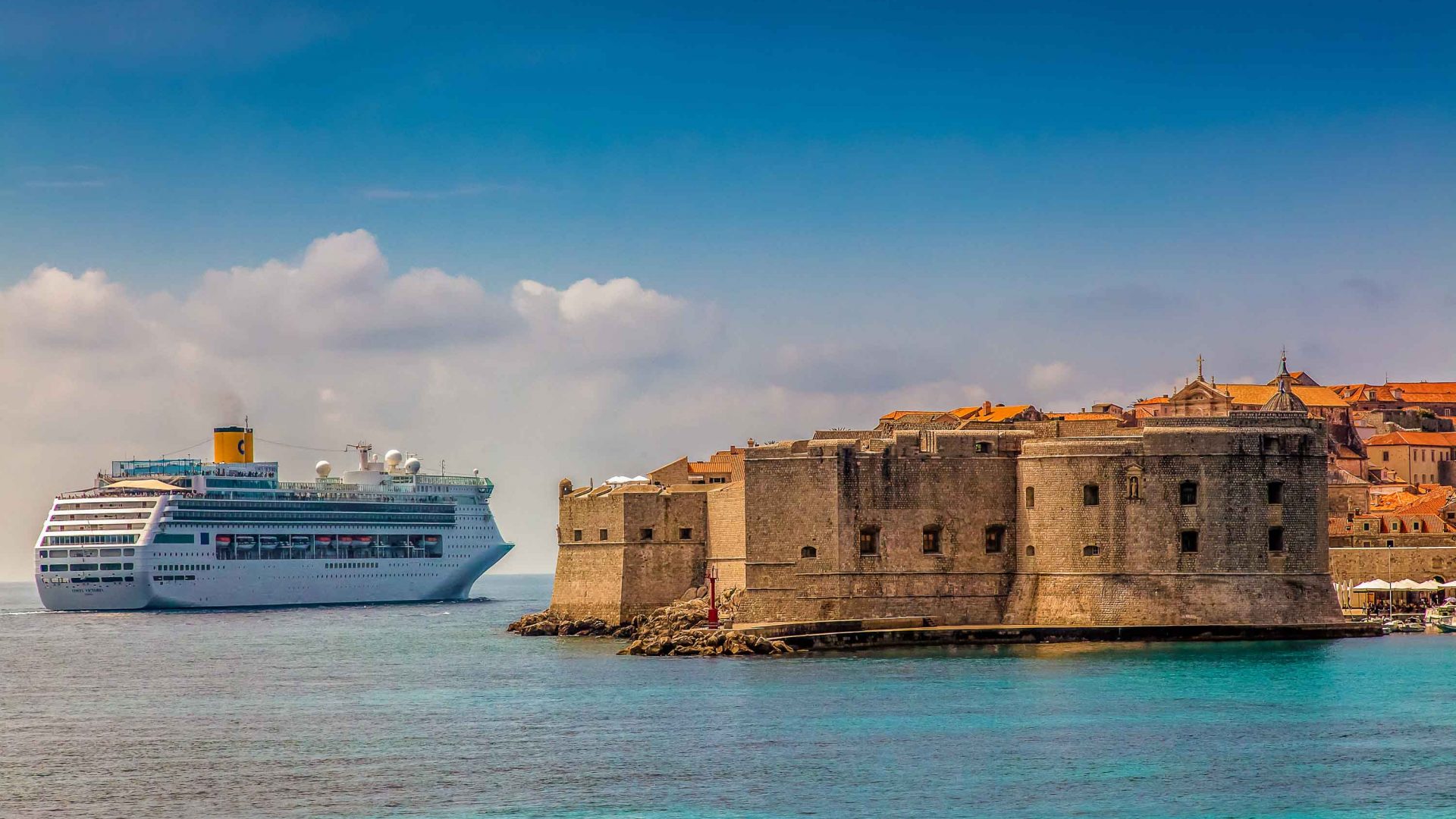 A cruise ship passes the stone walls of Dubrovnik.