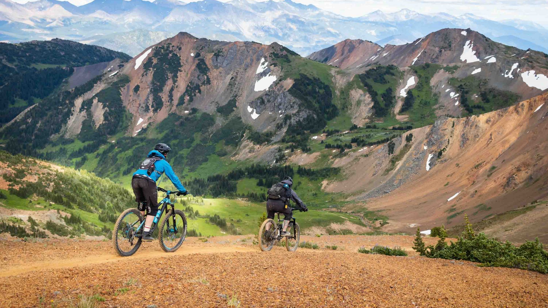 Mountain bikers on a gravel trail riding towards mountains.