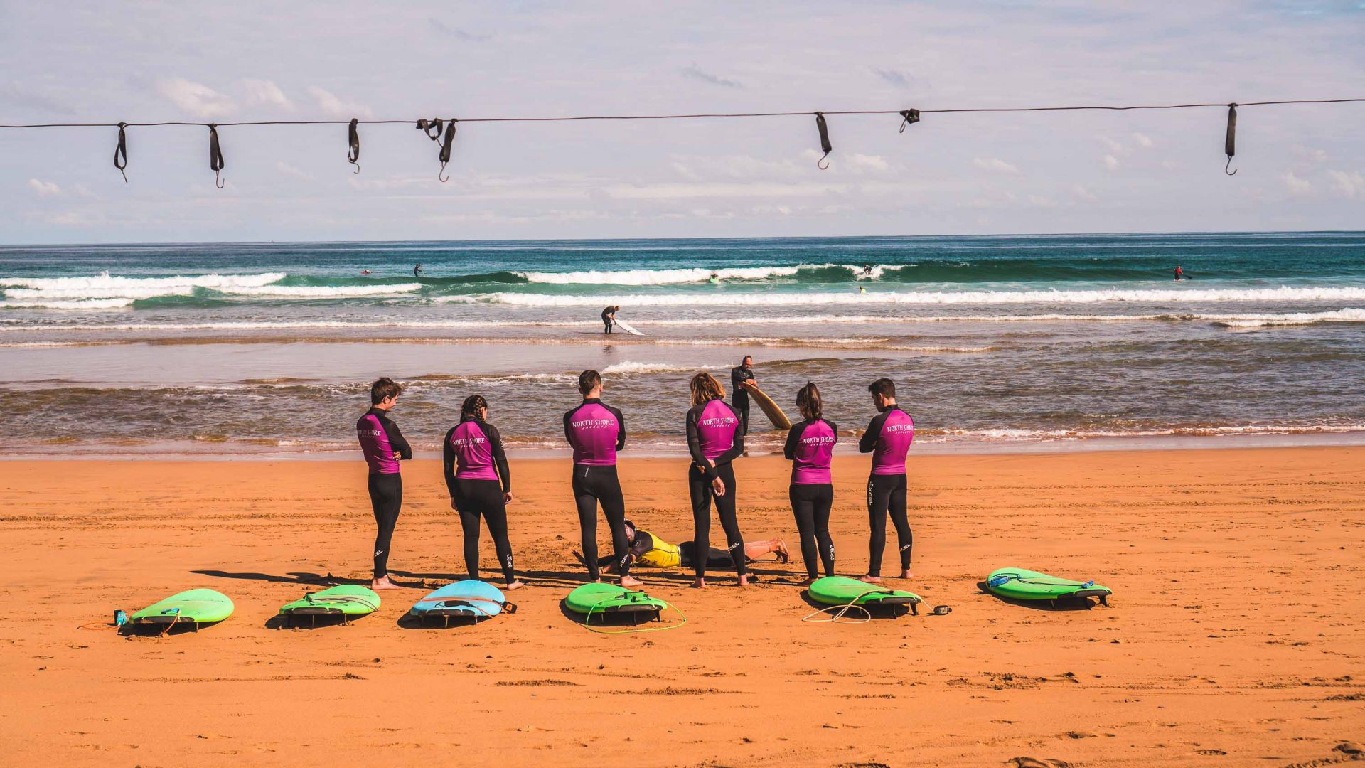 A guide teaches surfing to a group of people.