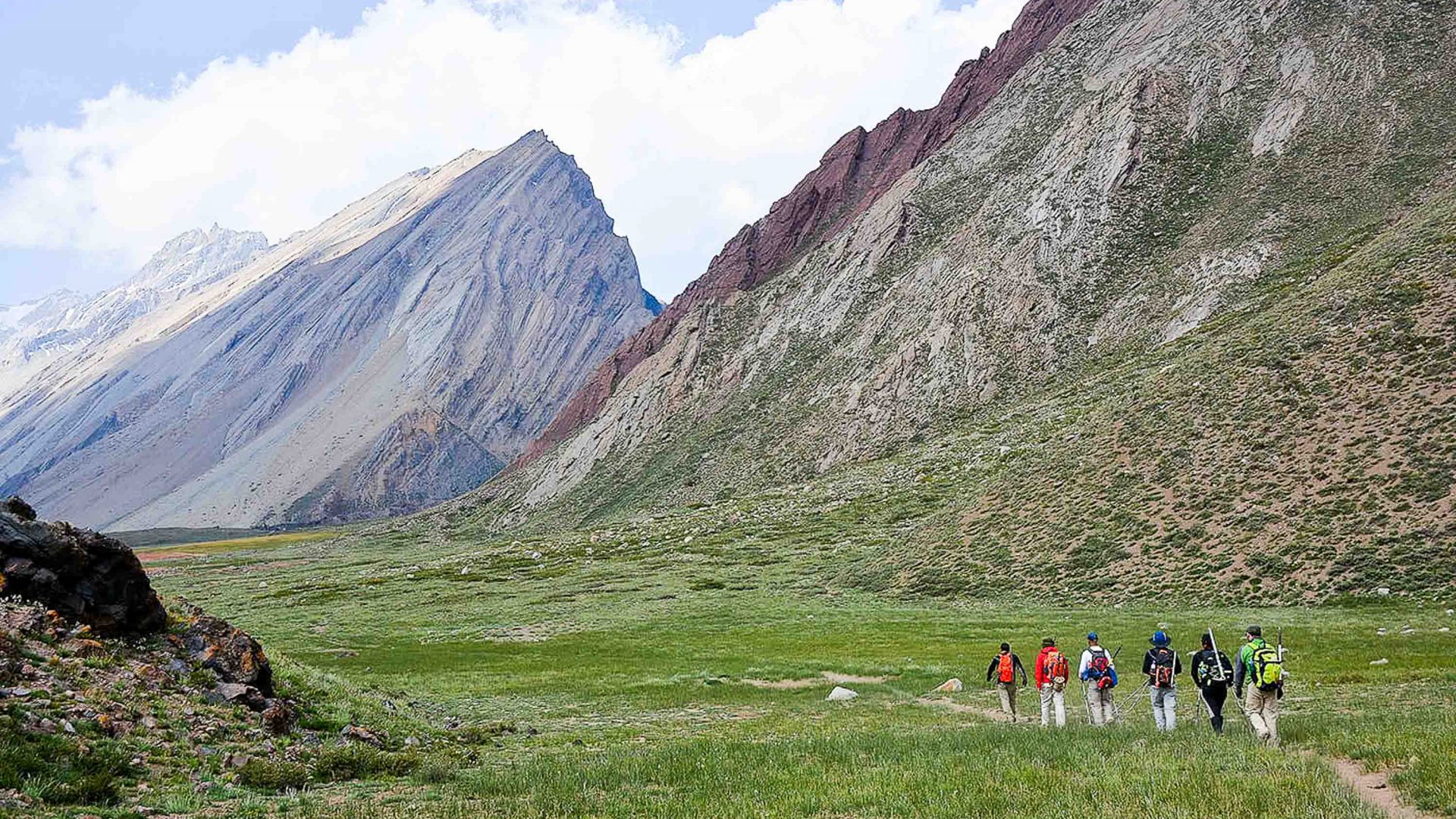 Hikers walking up a green valley.