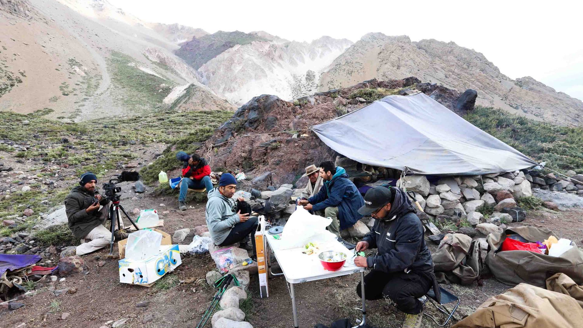 Hikers eat at a table in the mountains.