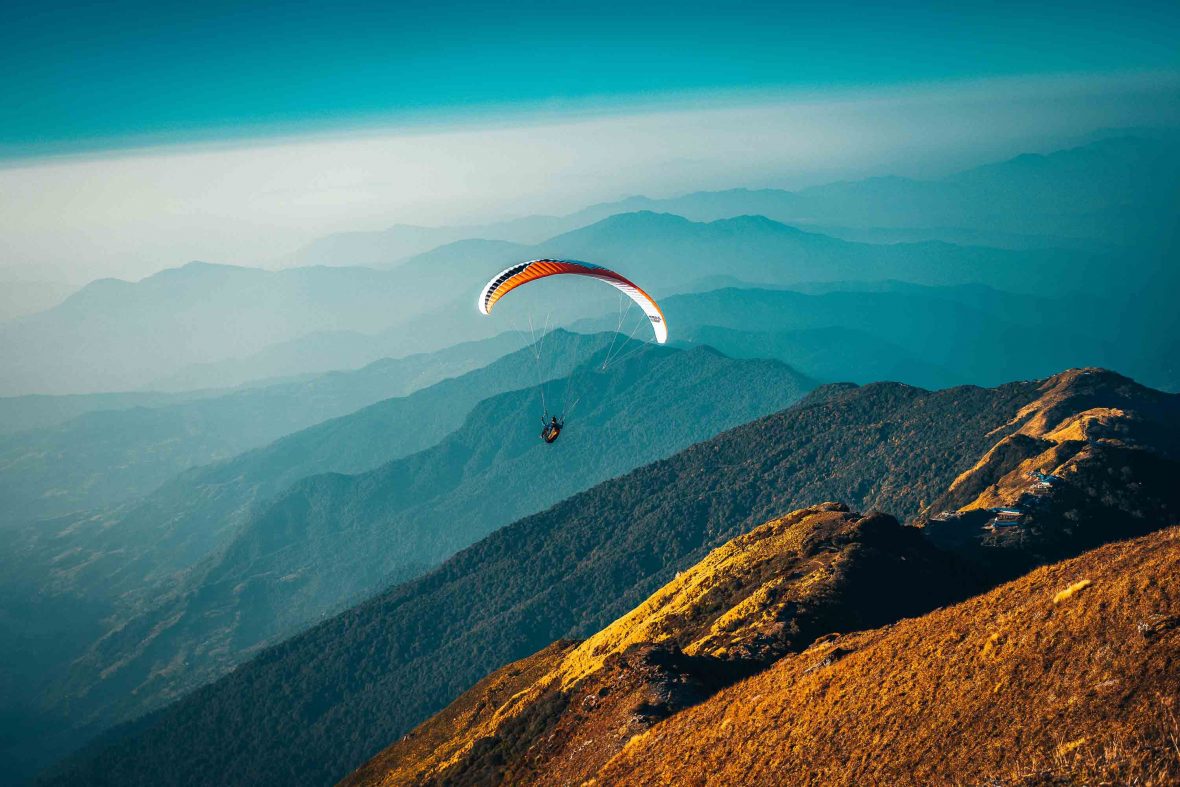 A paraglider flies over mountains..