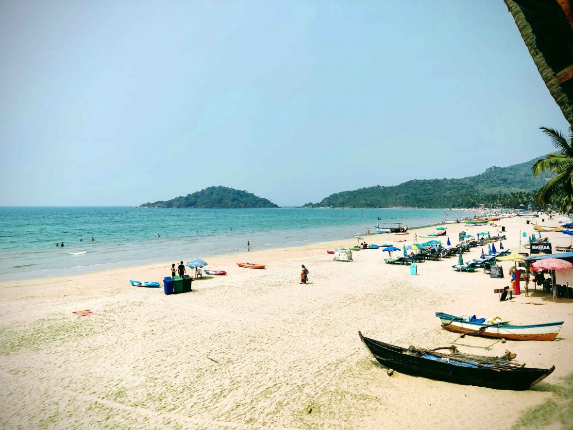 A beach in Goa with small boats, white sand and turquoise water.