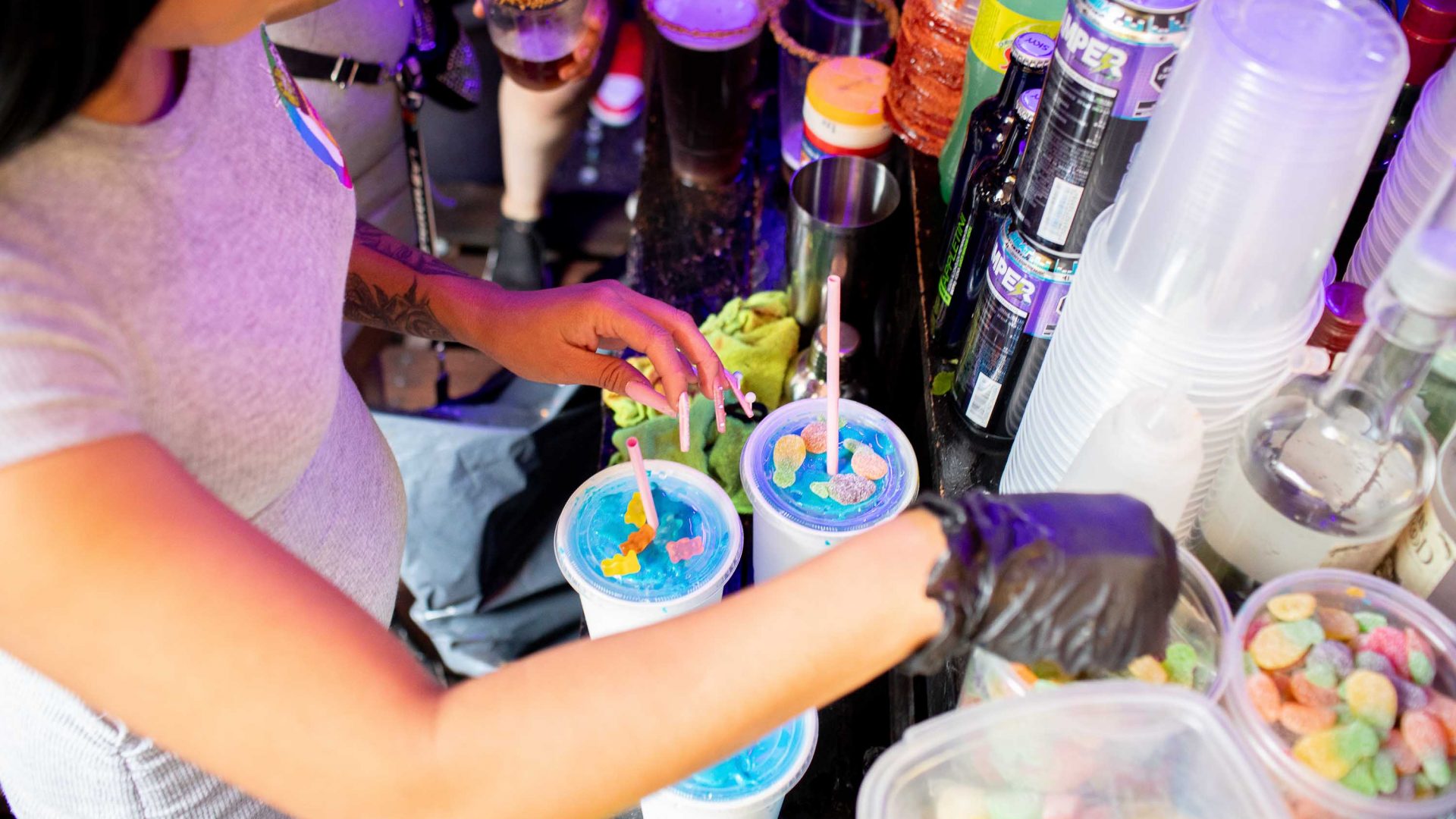A person's hands can be seen making blue candy covered micheladas.