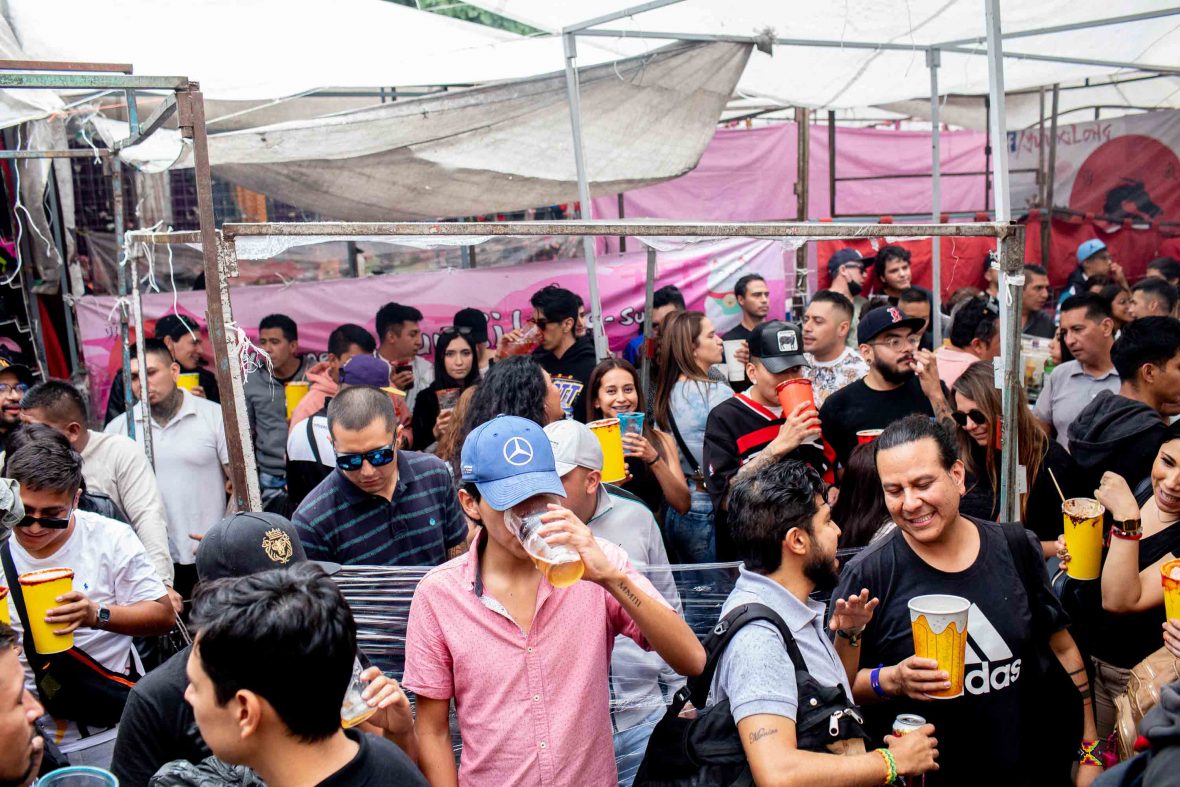 Party goers in a pink space drinking micheladas.