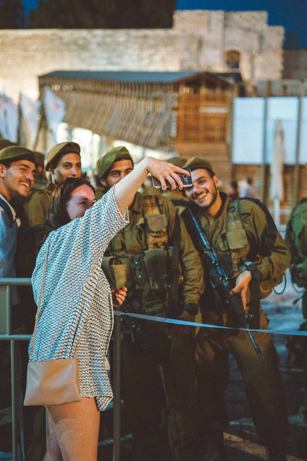 A tourist takes a selfie with soldiers.