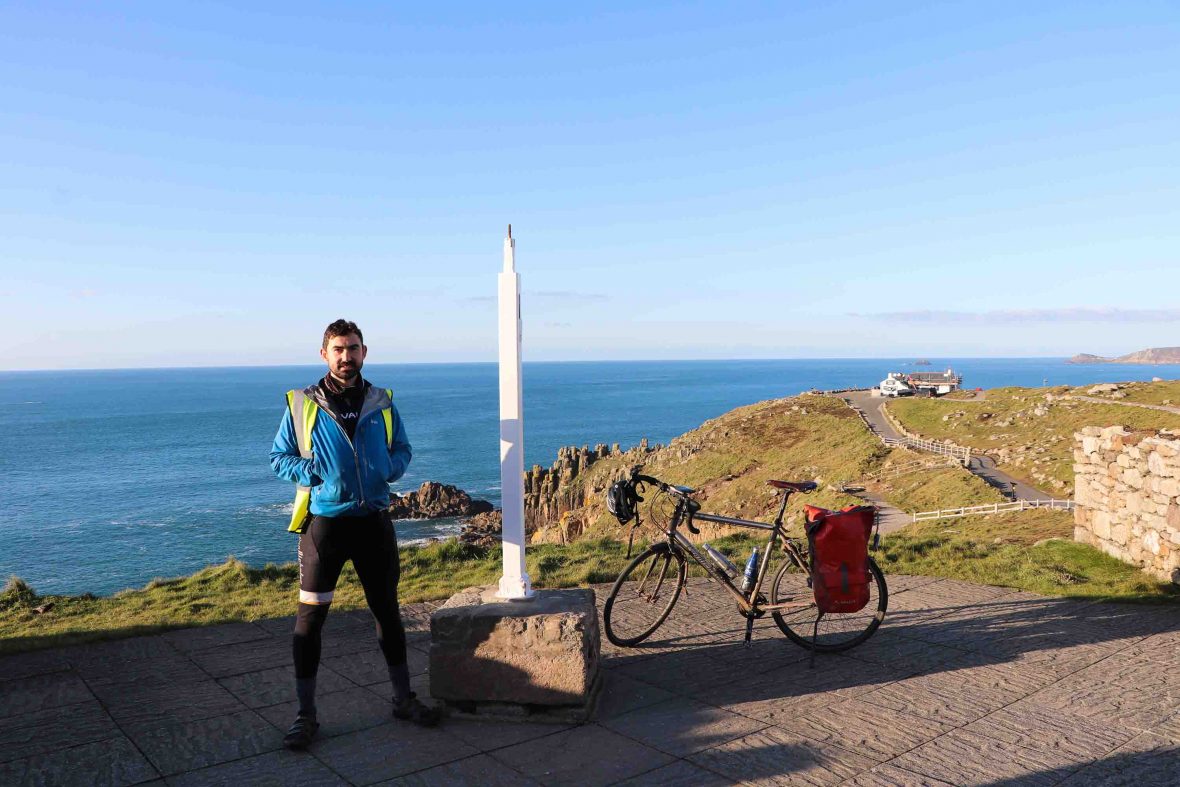 Simon stands next to a monument at Lands End.