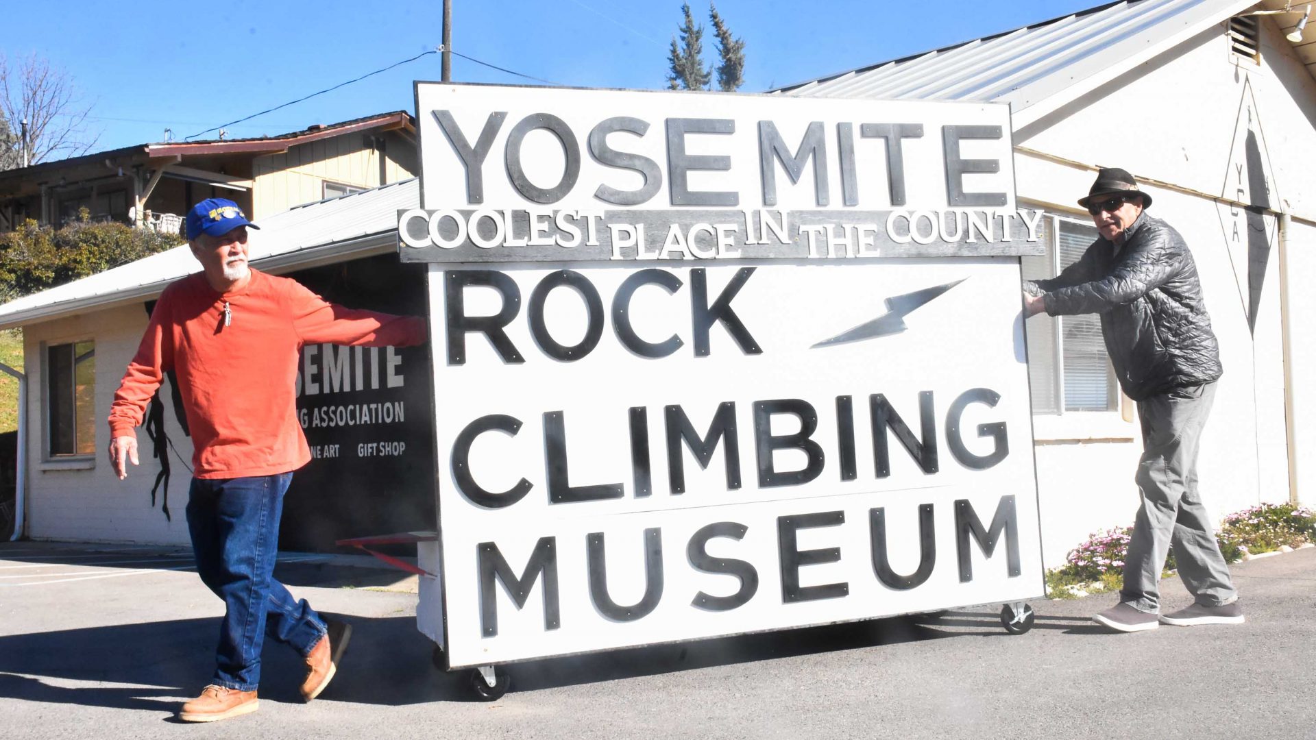 Two men hold a museum sign.