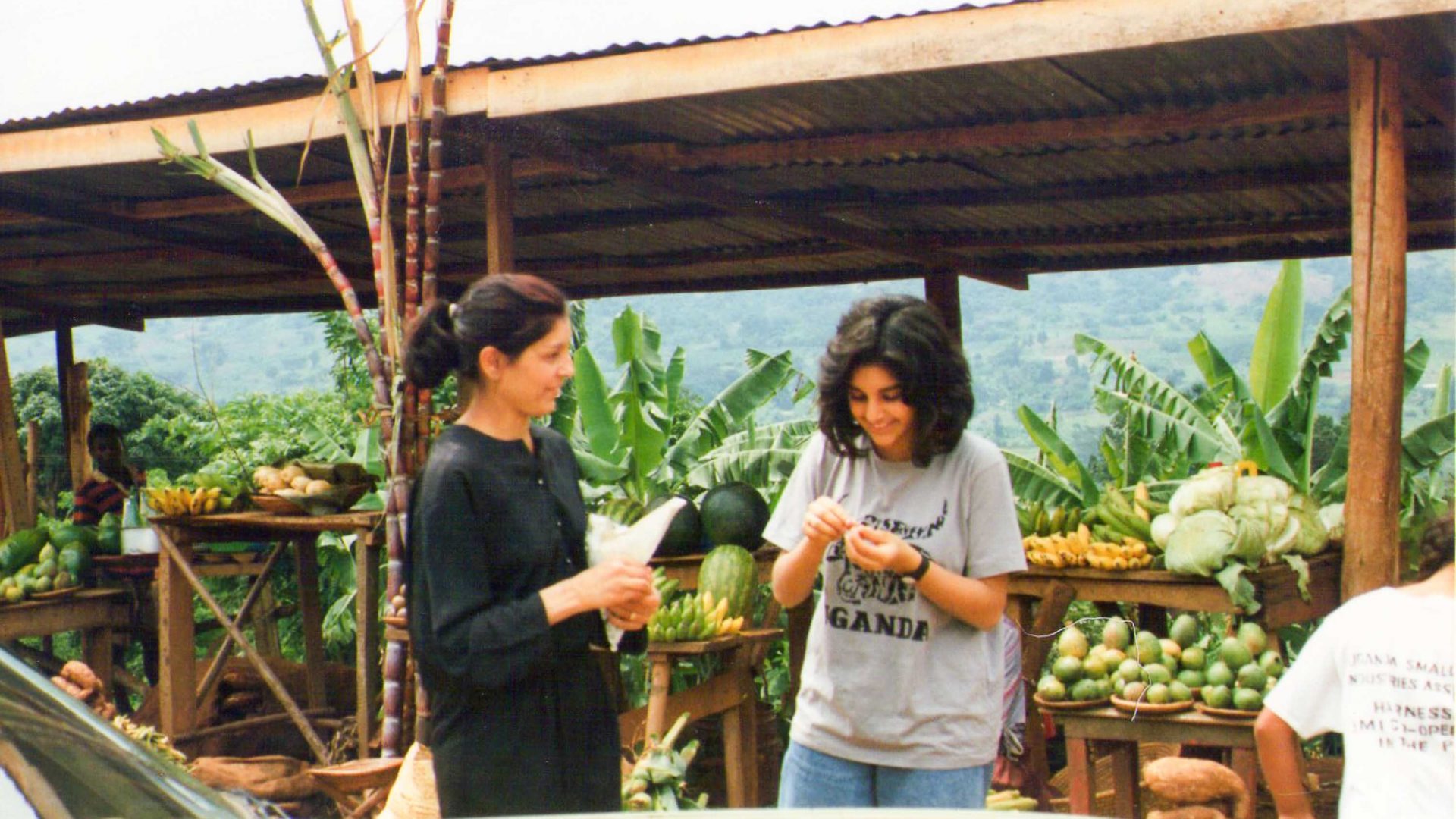 An old photo of two women at a fruit market.