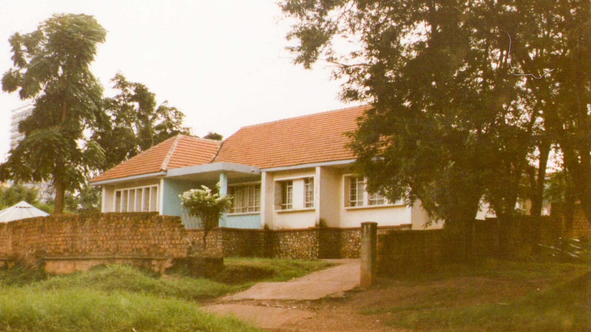 An old photo of a blue and white home with a tree out the front.