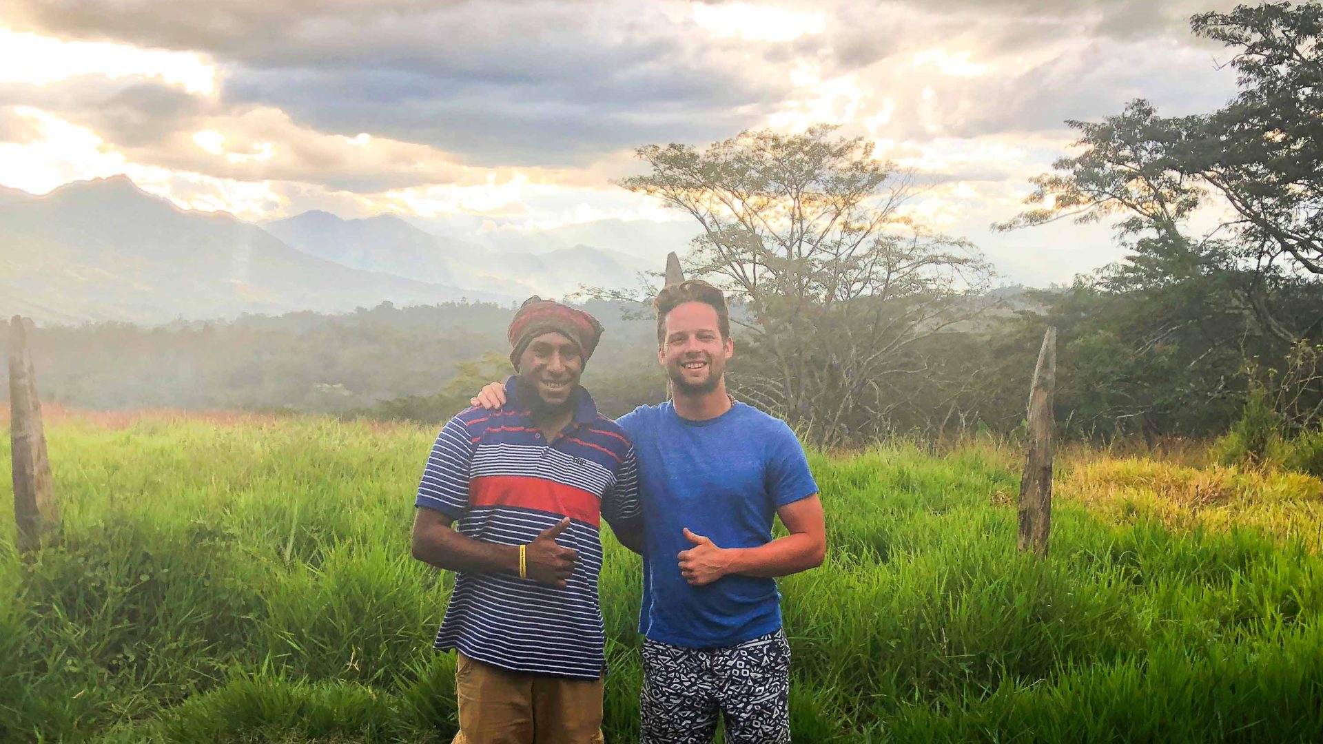 Johnny and his host in PNG smile in front of a sunset.