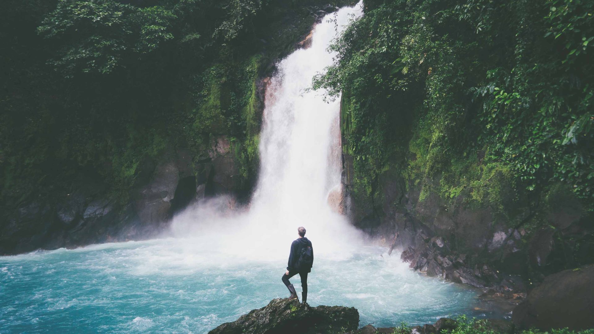 A man looks out at a waterfall.