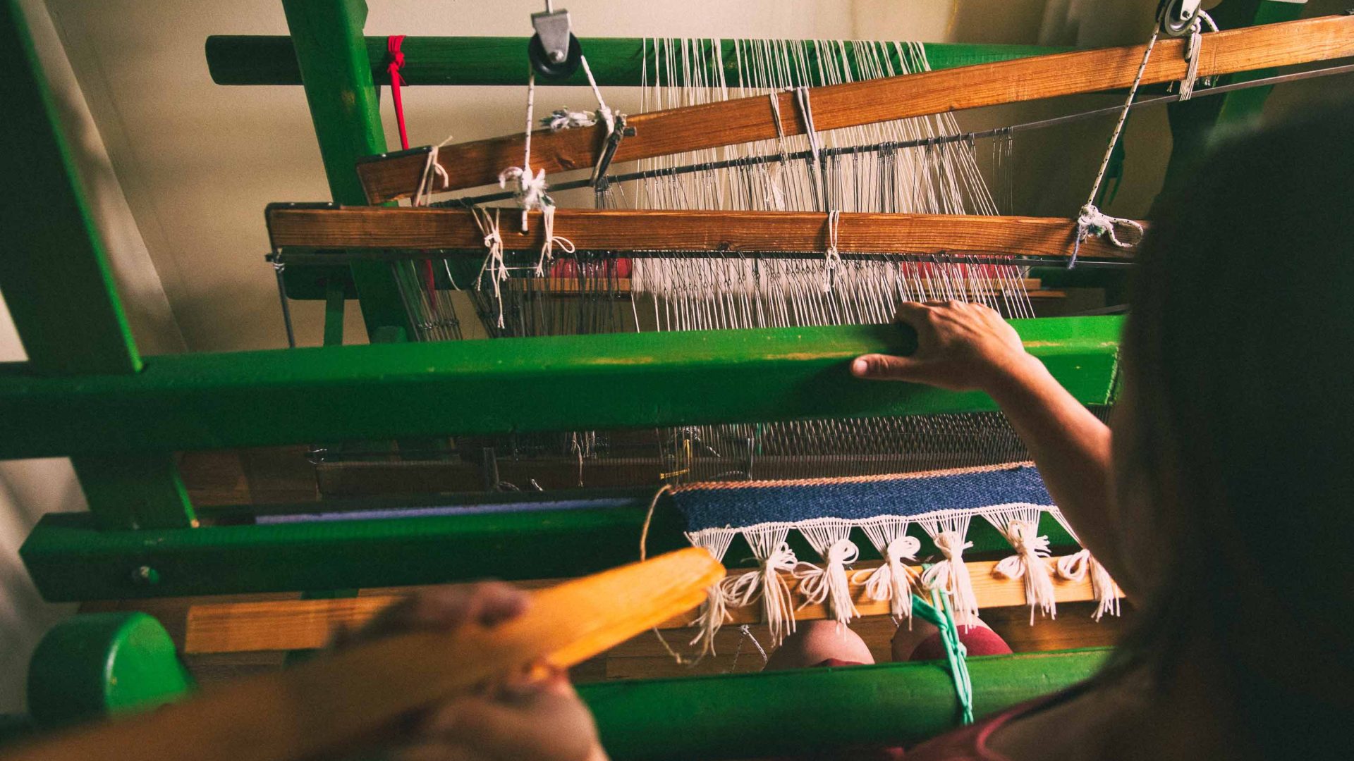 A wool loom with hands using it.
