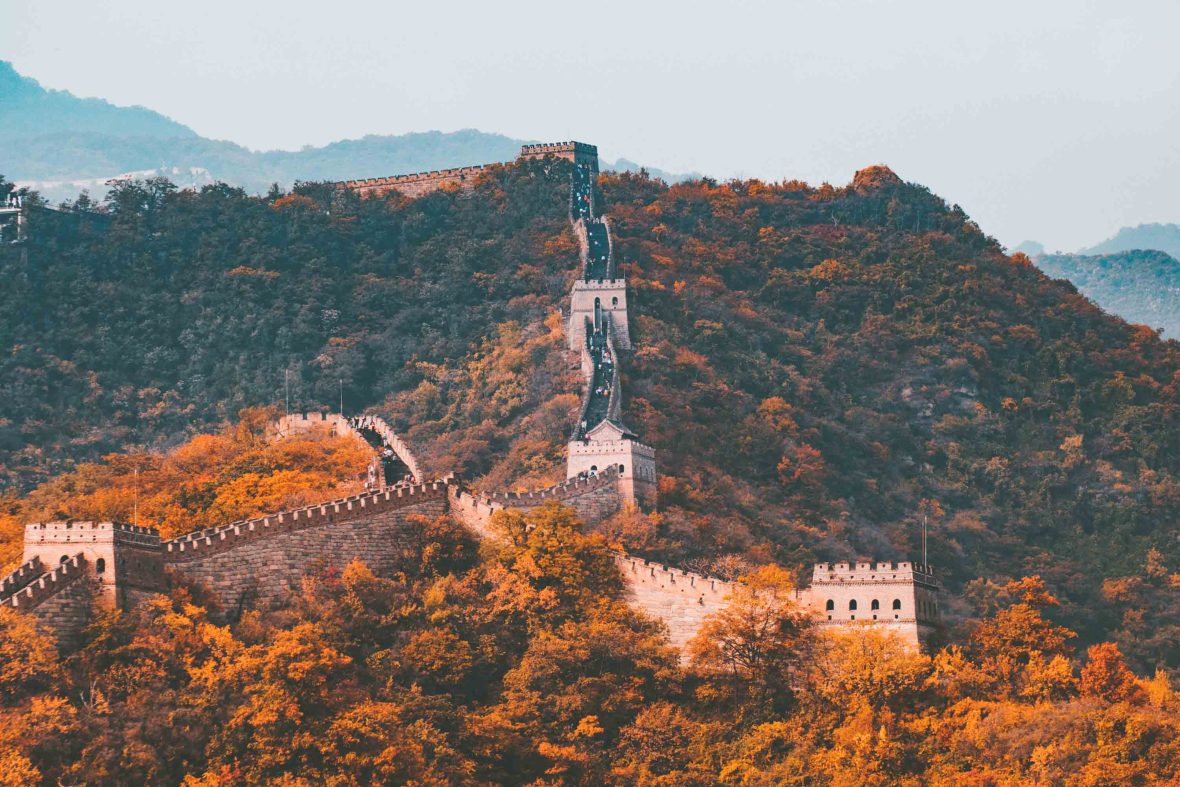 The Great Wall of China, surrounded by trees and hills in soft light.
