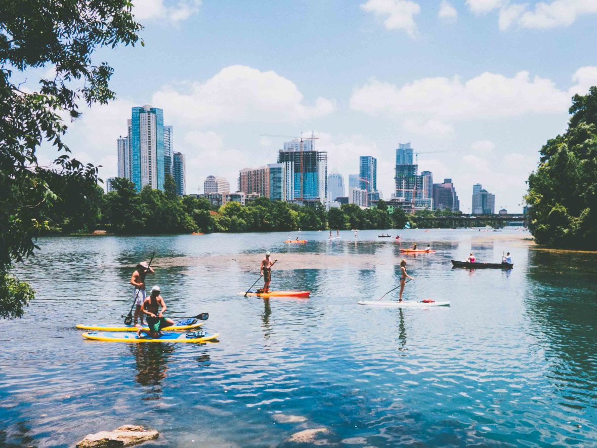 People on stand up paddle boards with the city in the background.