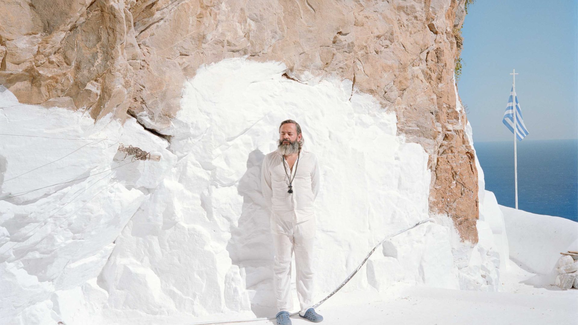 A man in white against a painted white rock face.
