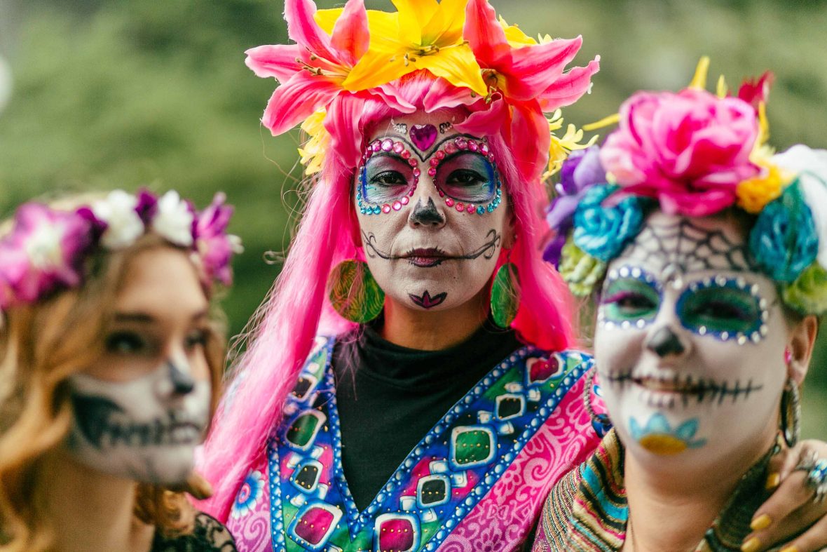 Three women in face paint look to camera.
