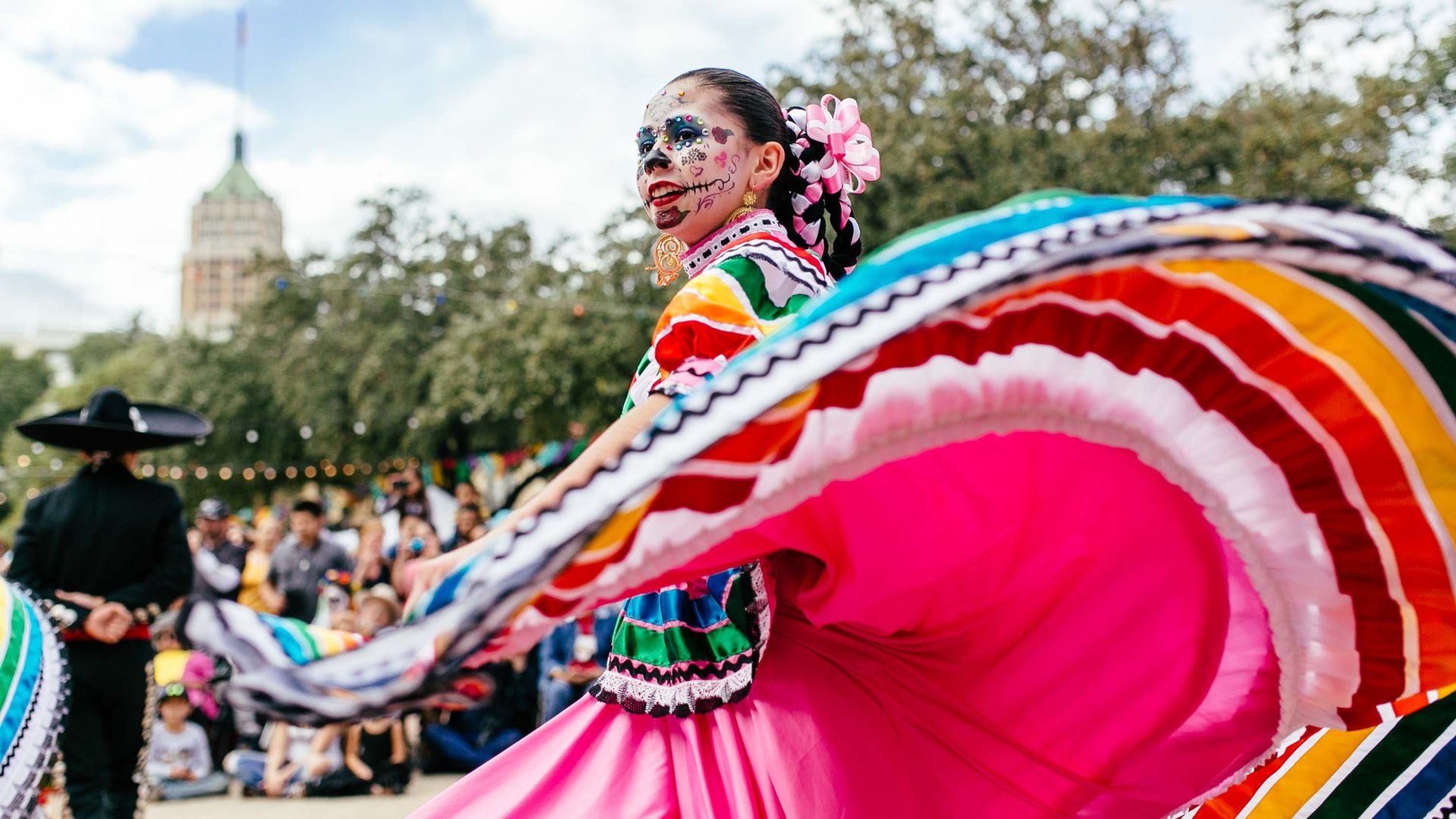 A dancer in face paint wearing a big pink skirt.