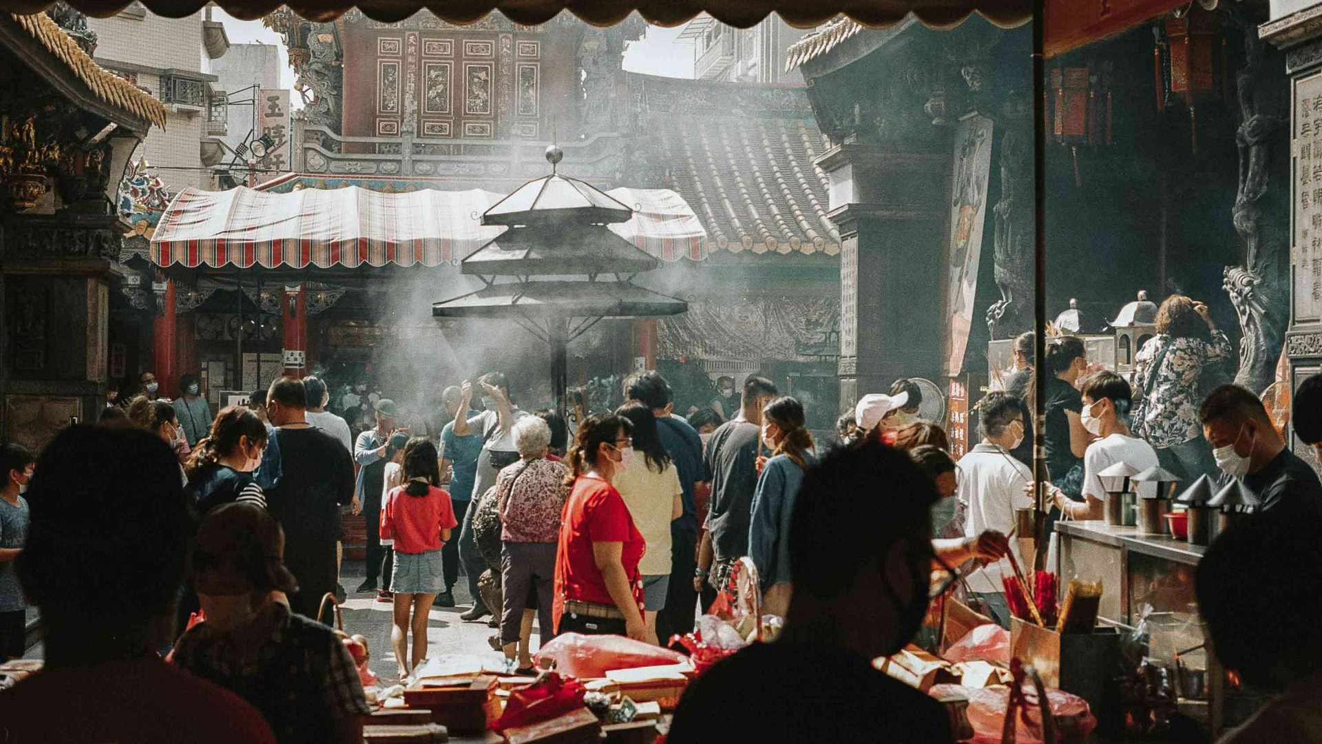 Incense burns and people gather in a smoky temple.