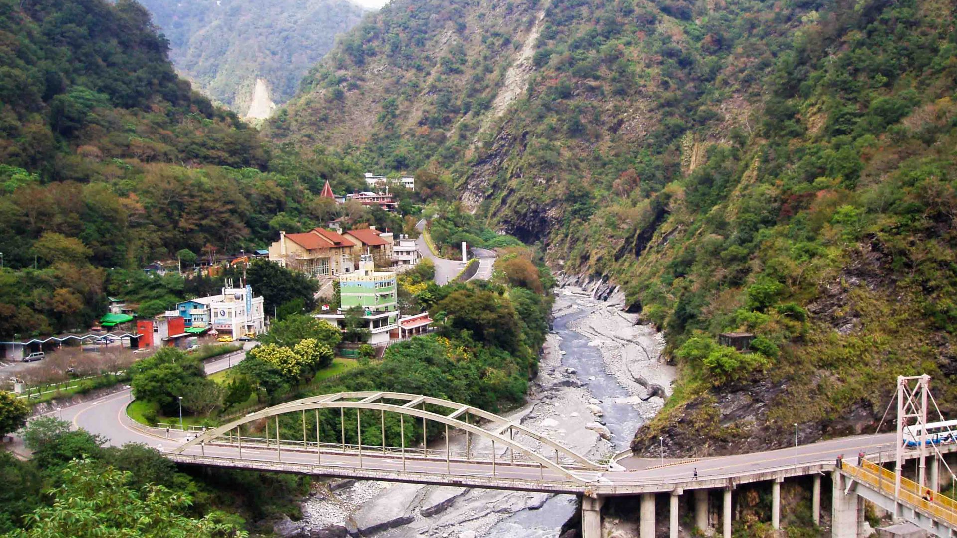 A bridge over a gorge with a small town to the left, flanking the water.