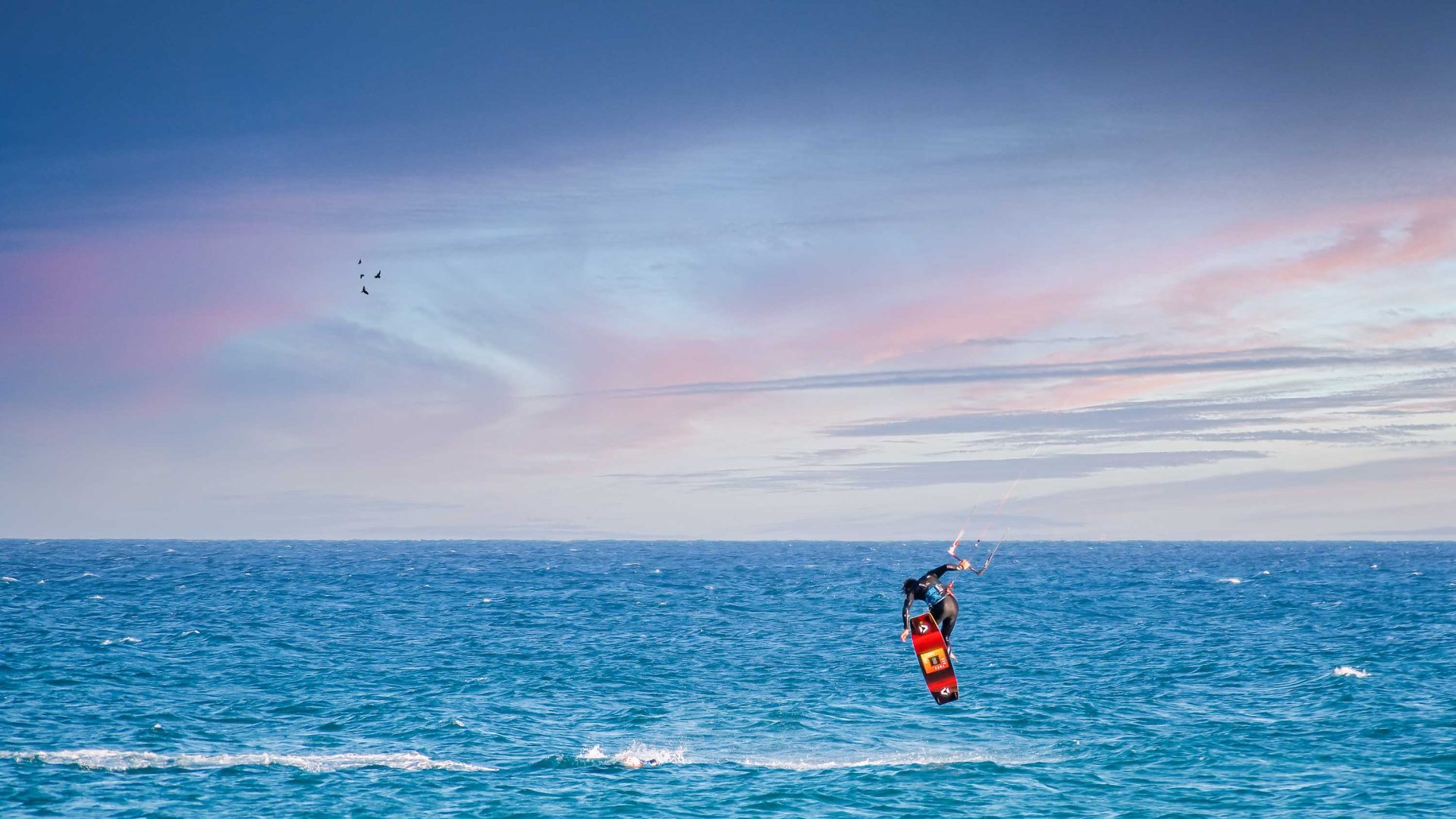 A kitesurfer jumps on a wave.