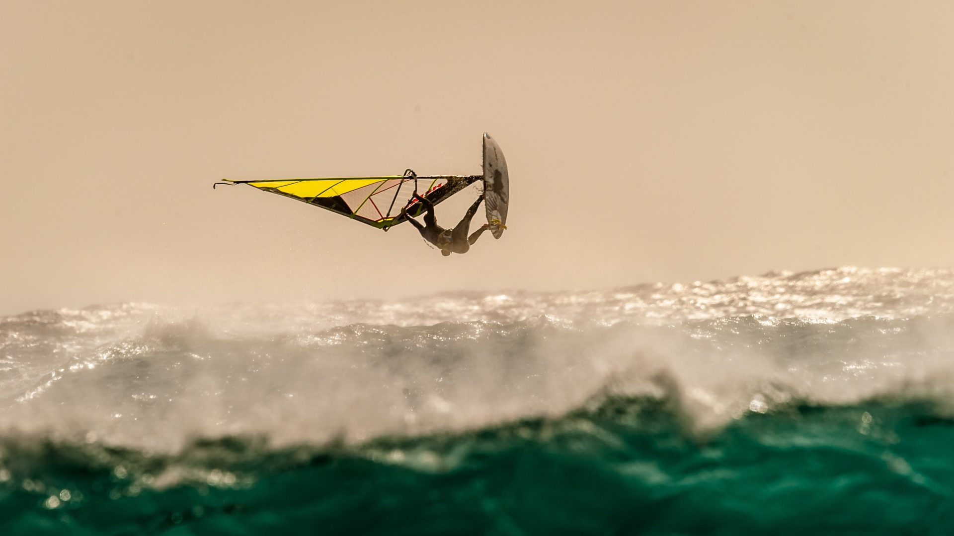 A windsurfer takes to the air above the water.