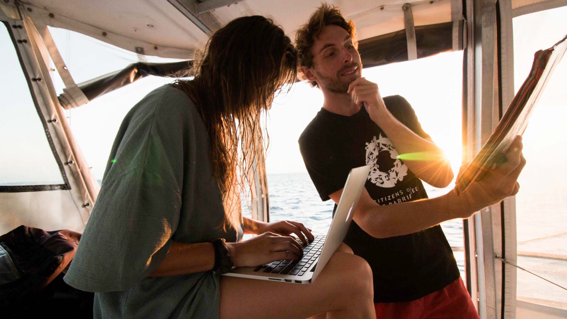 A man and a woman look at data aboard a boat.