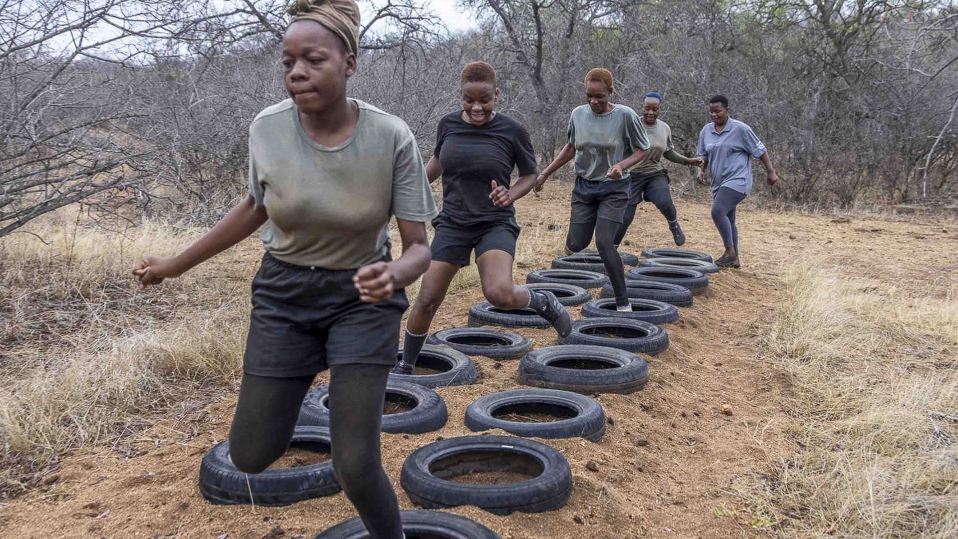 Women run through car tyres as part of their training.