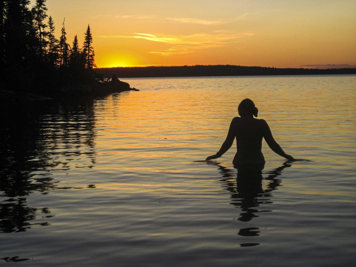 A woman skinny dips at sunset.