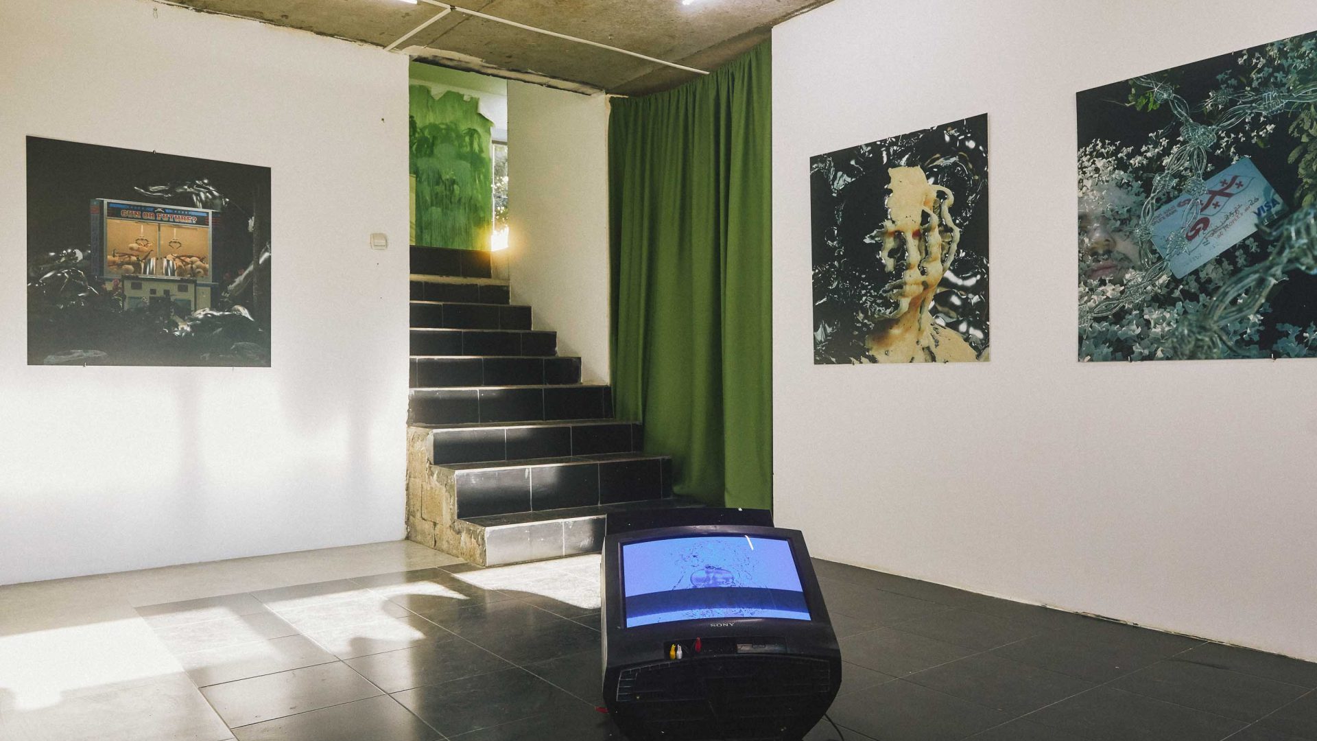 An art gallery with a TV screen and art on the walls.