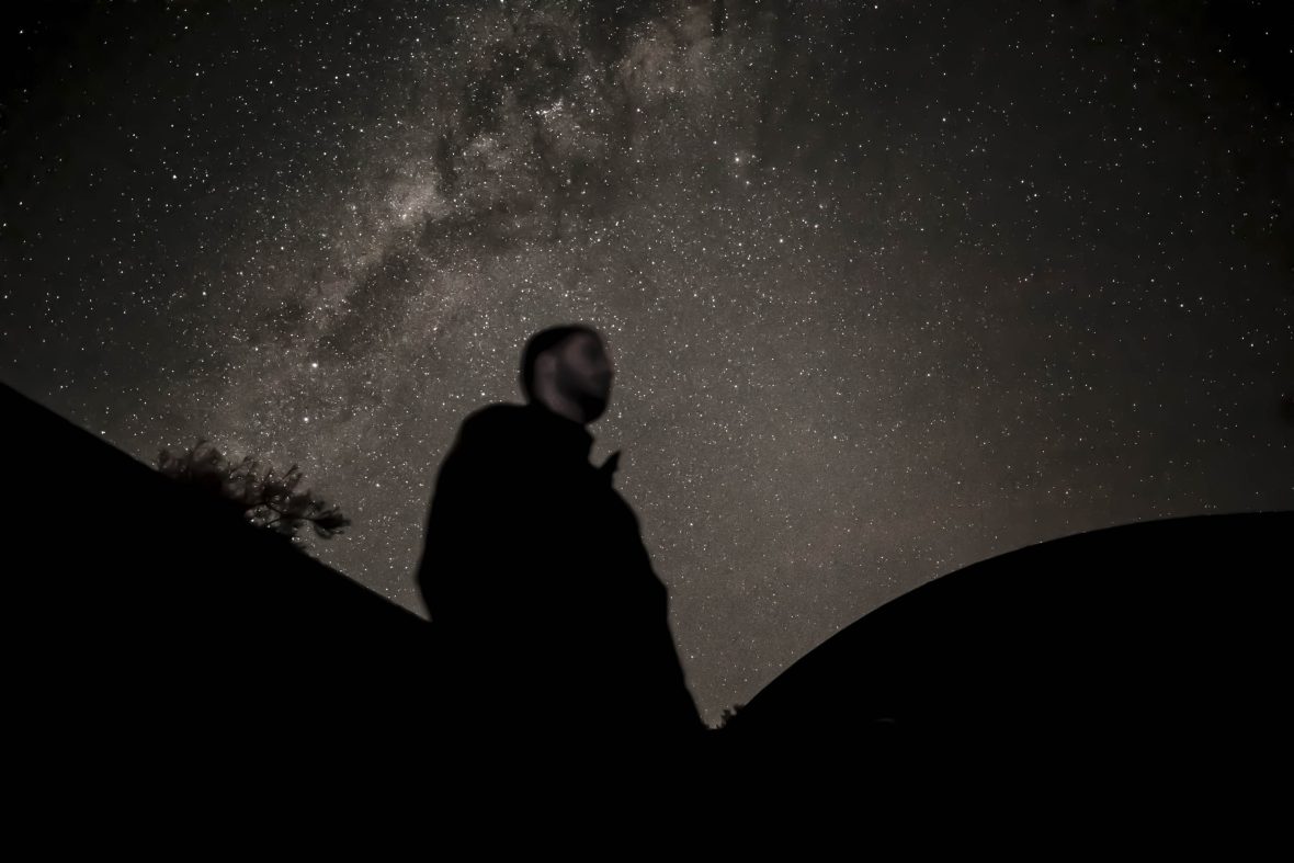 The silhouette of a man against a night sky.