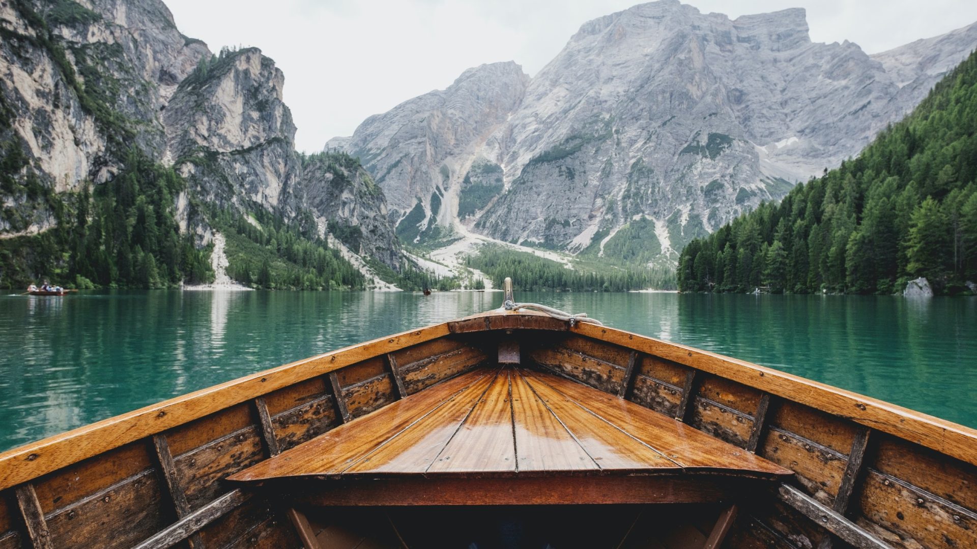 A wooden boat sailing on a lake with mountain views.
