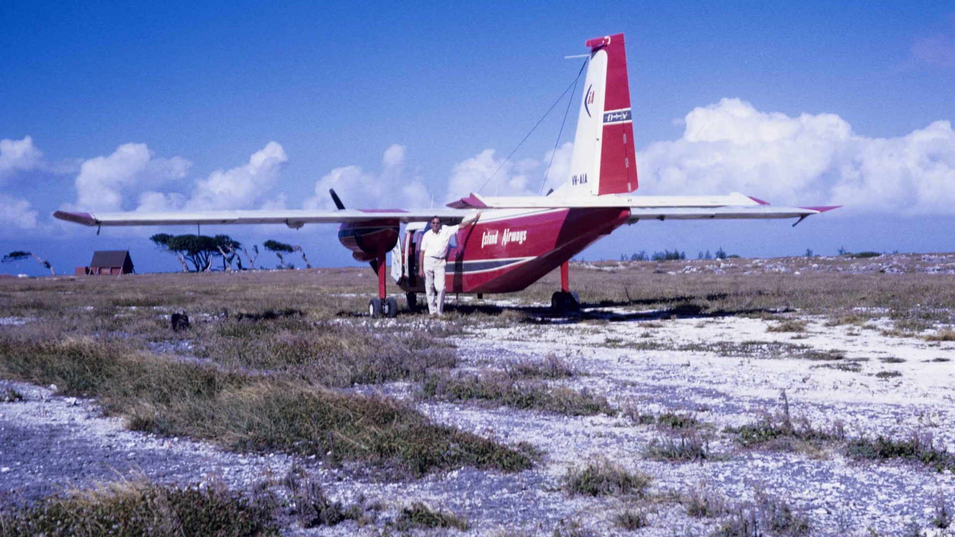 A man next to a small red and white plane.