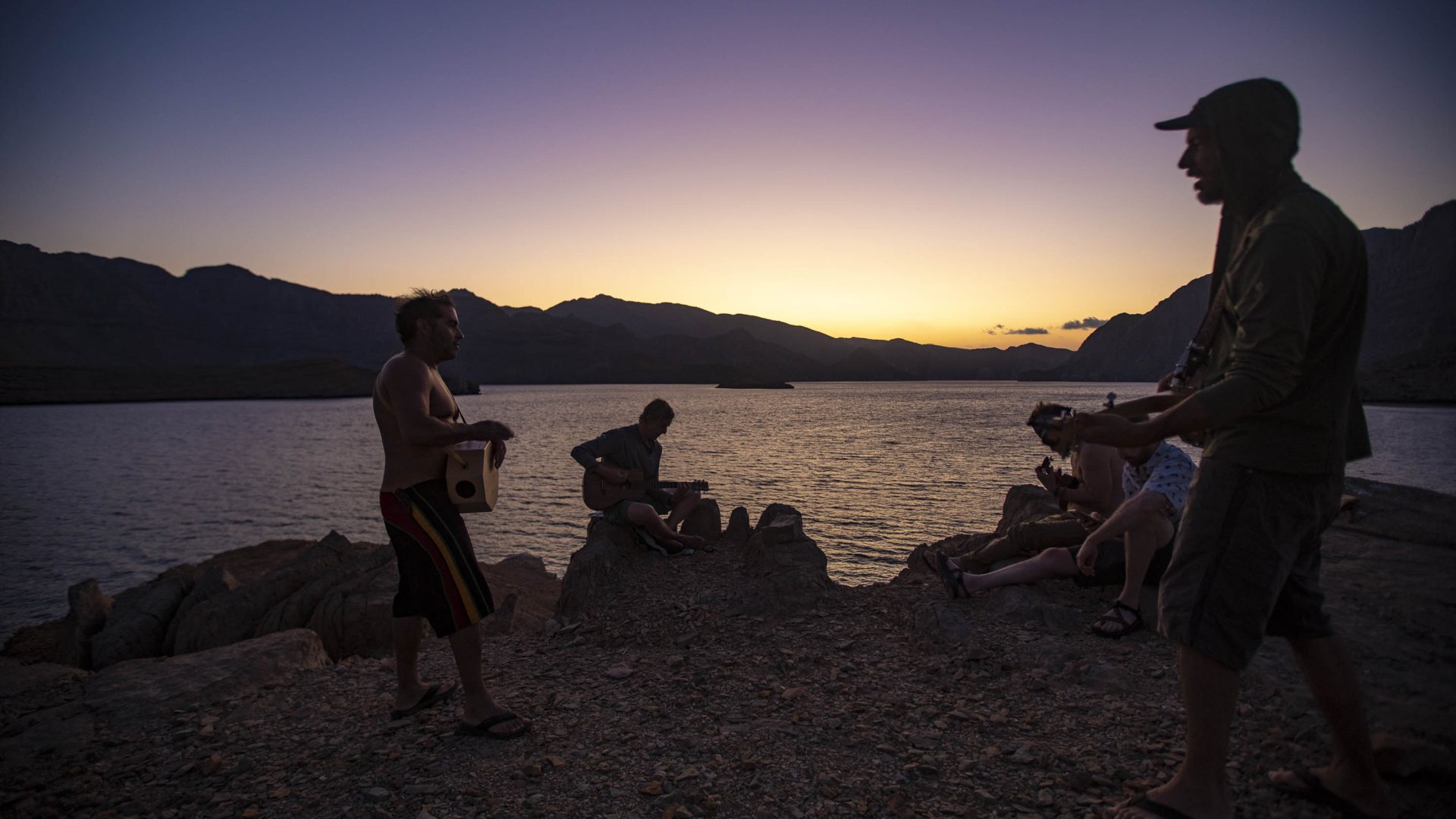 A group of friends play their banjos as dusk falls.