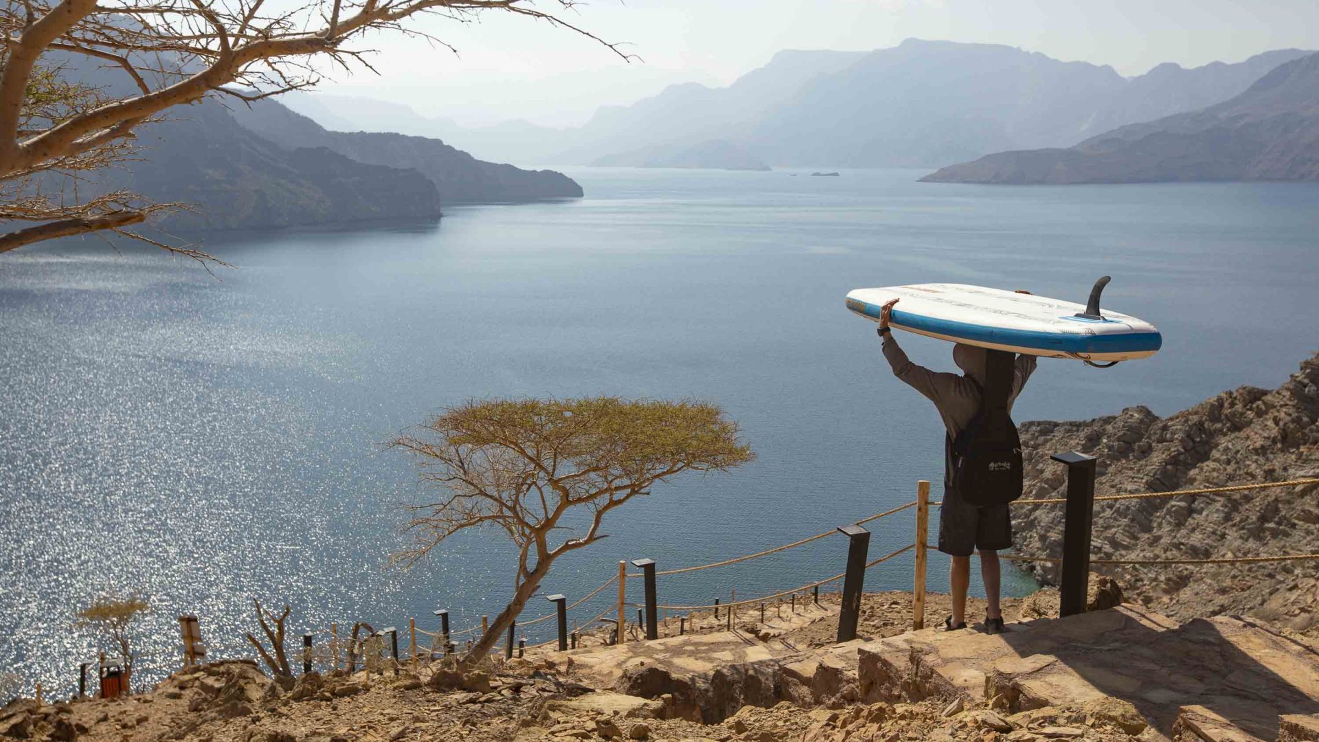 A person with a paddleboard on his head looks out over the view.
