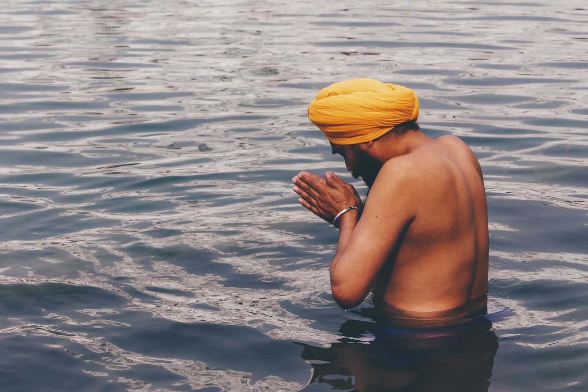 A Sikh man in an orange turban in the water..