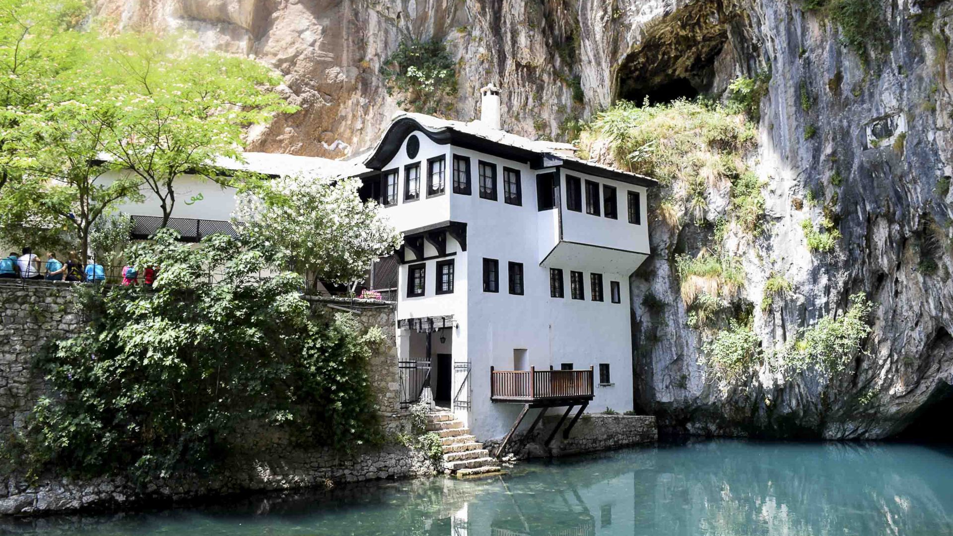 A multi-story white building sits on the very edge of a blue river.